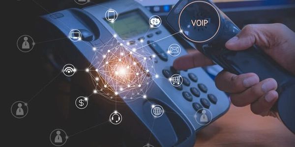 Hand holding a VOIP phone handset with digital icons overlay.