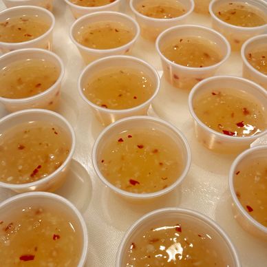 Small cups filled with a light sauce containing chili flakes and garlic.