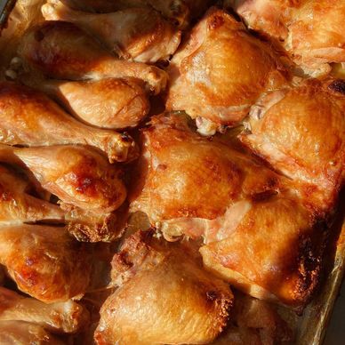 Golden-brown roasted chicken drumsticks and thighs on a tray.