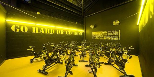 Indoor cycling room with motivational yellow and black decor.
