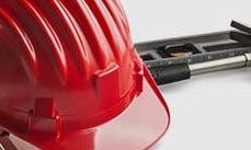 Red construction helmet with hammer and measuring tools on white background.