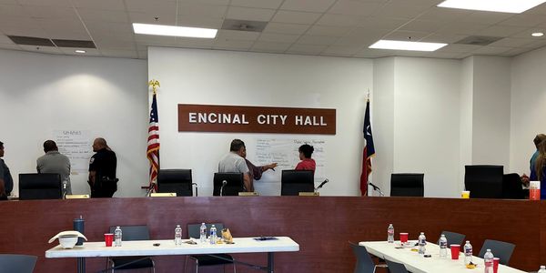 People discuss notes on a board at Encinal City Hall meeting room.