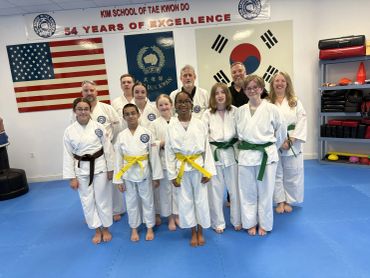 A group of taekwondo students and instructors posing in a dojang.