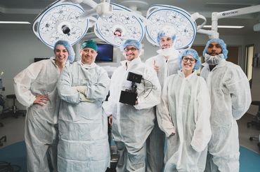 Video Aces Video crew and surgical team in gowns under operating room lights