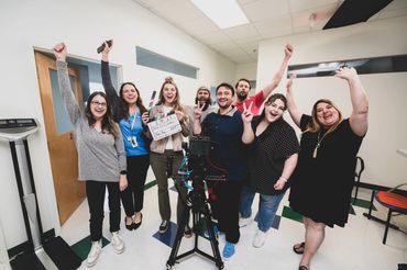 Clinic staff and Video Aces Video crew cheering with a slate after wrapping a shoot