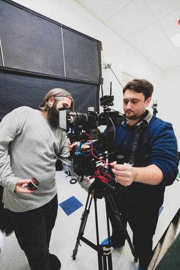 Two Video Aces Video crew members operating a cinema camera on a tripod in a clinic