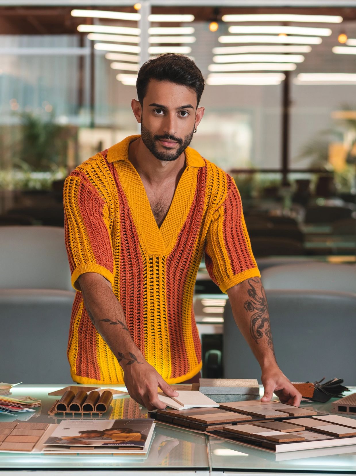 Homem com suéter colorido escolhendo amostras em uma mesa.