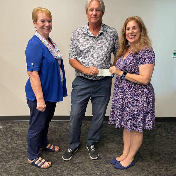 Two board members awarding grant funds to man.