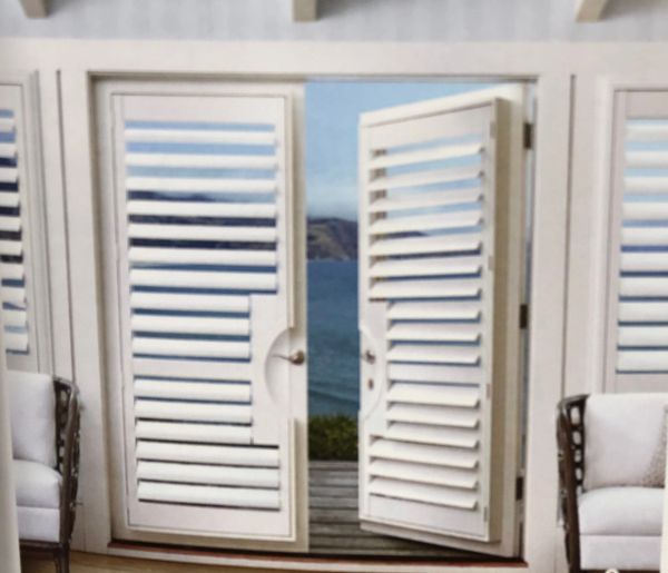 White louvered doors opening to a scenic ocean view with mountains in the distance.