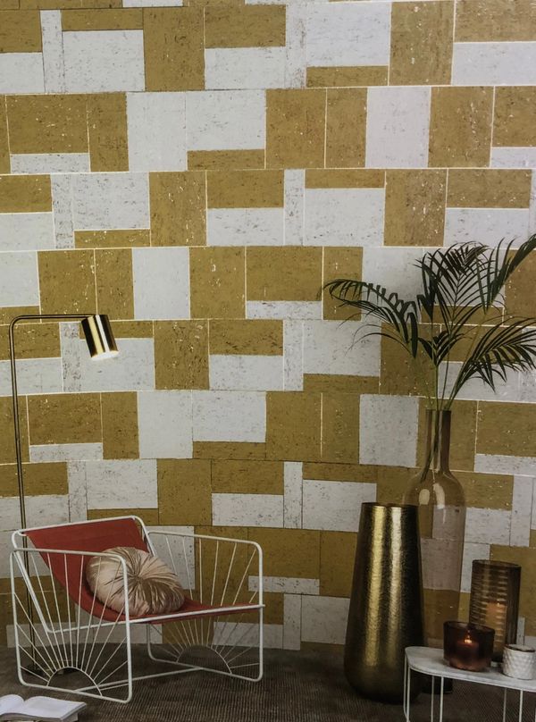 Modern sitting area with a white metal chair, gold accents, and geometric wall design.