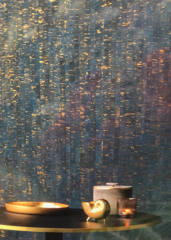 Decorative golden shell, tray, and candle on a table with textured blue and gold background.