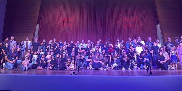 Large group photo on stage with purple lighting.