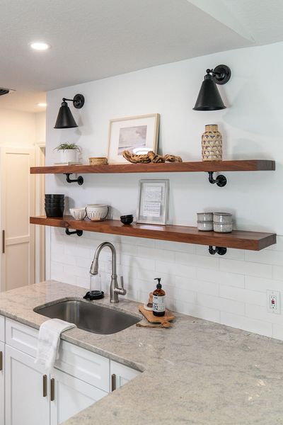Minimalist kitchen with wooden shelves and white countertops.
