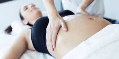 Pregnant woman receiving a belly massage to help with pregnancy pain and fetal positioning.