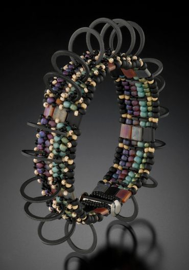 Cuff of handwoven and layered glass beads Steel C-clamps.