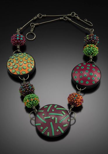 Necklace of hand formed polymer forms and handwoven and layered glass beads. Steel wire.