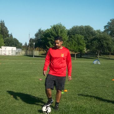 Man in red shirt playing soccer on a grassy field.