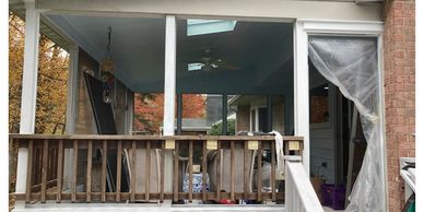 Back porch of a house under renovation with torn plastic sheeting.