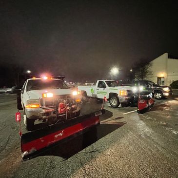 Several work trucks parked in a lot illuminated by night lights, indicating commercial activity