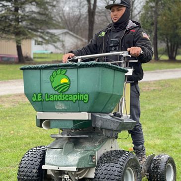 An employee of J.E. Landscaping operating work equipment as part of landscaping services.