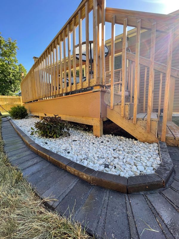 A wooden deck with rocks and a wooden railing
