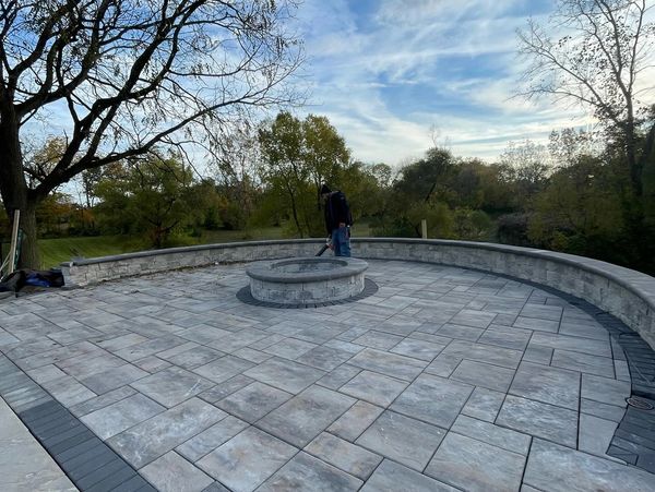 A man standing on a stone patio next to a tree