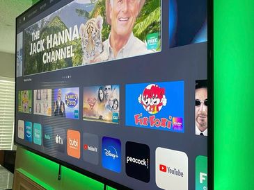 Smart TV screen showing various streaming apps with green ambient backlighting.
