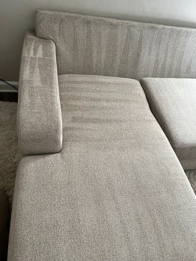 Close-up of a beige fabric sectional sofa with textured upholstery.