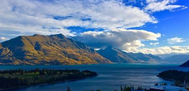 Lake surrounded by mountains under a partly cloudy sky.