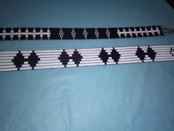 Two black and white beaded bracelets with geometric patterns on a blue surface.