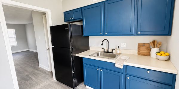 Bright kitchen with blue cabinets and black fridge.