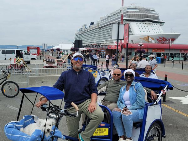 Group riding pedicabs near a cruise ship at Victoria port.