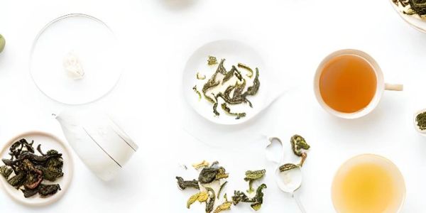 Tea leaves and brewed tea cups arranged on a white surface.