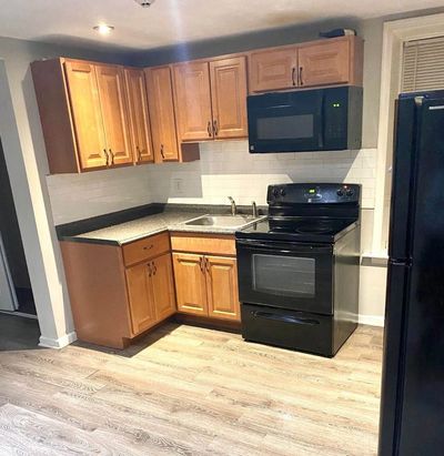 Cozy kitchen with wooden cabinets and black appliances.