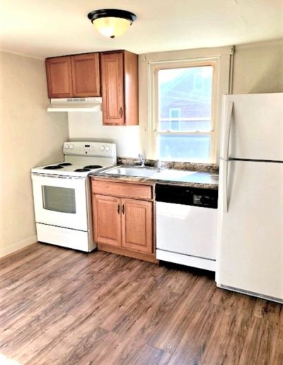 Compact kitchen with white appliances and wooden cabinets.