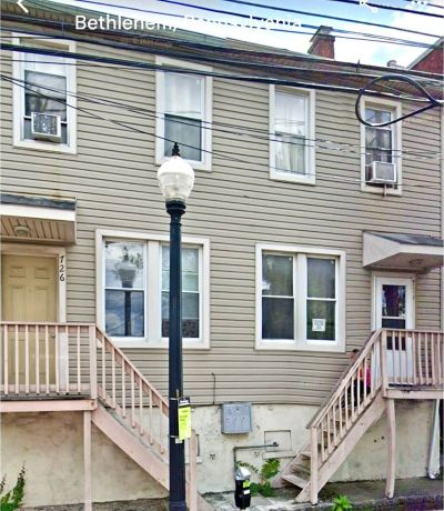 Two-story beige house with two staircases and a streetlight.