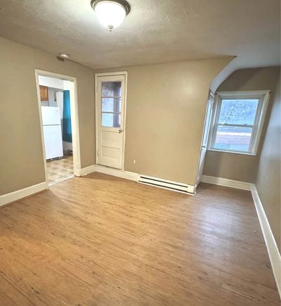 Empty room with wooden floor and beige walls.