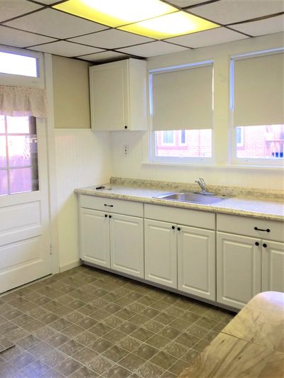 Clean kitchen with white cabinetry and tiled floor.
