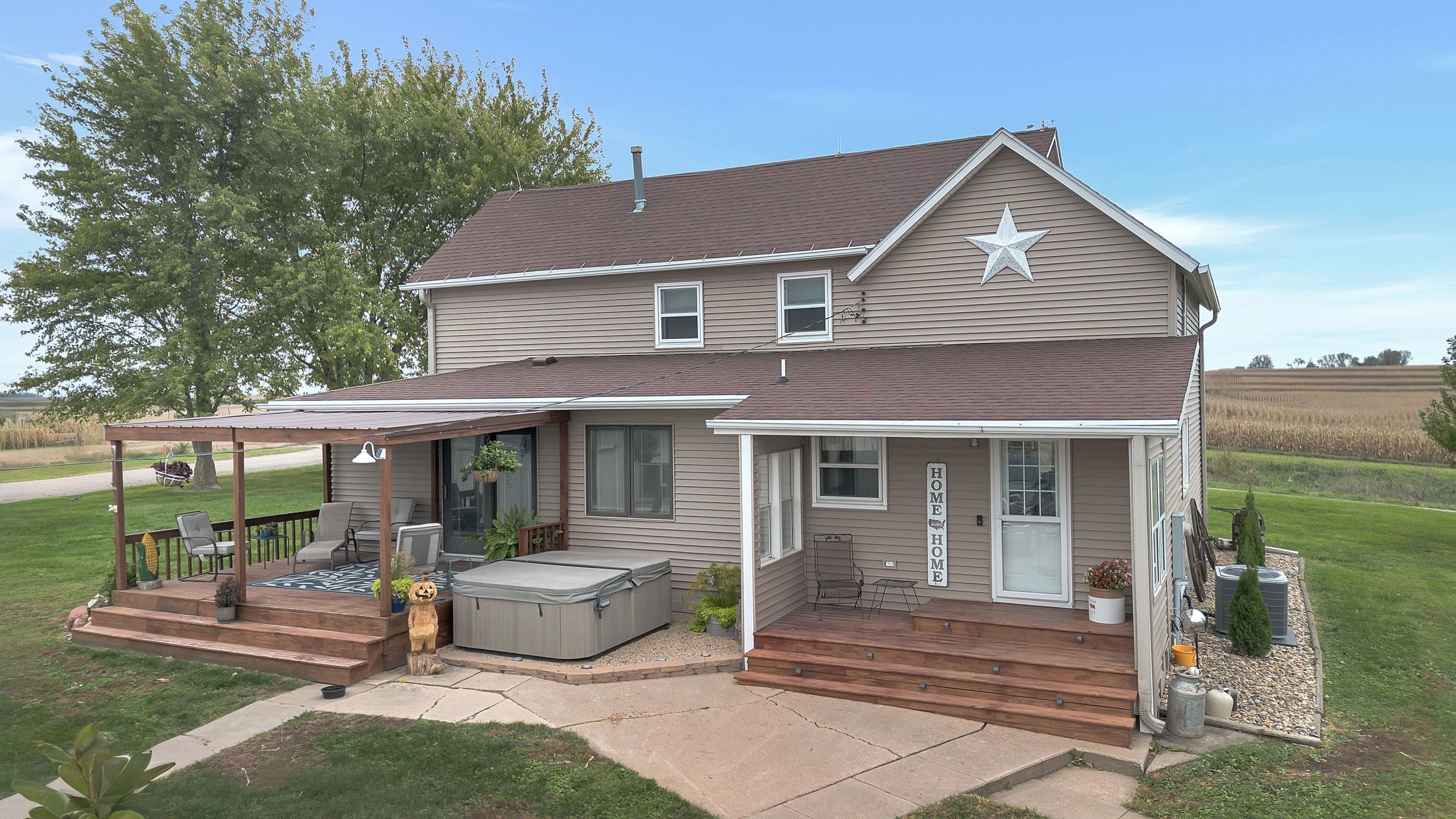 Cozy farmhouse with porch and hot tub in rural setting.