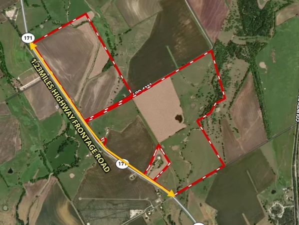 Aerial farmland with red boundary and highway frontage road.