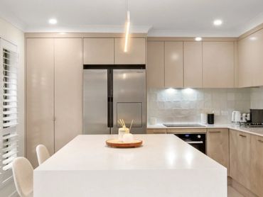 ARCOVE kitchen renovation with a white island, neutral cabinetry and plantation shutters.
