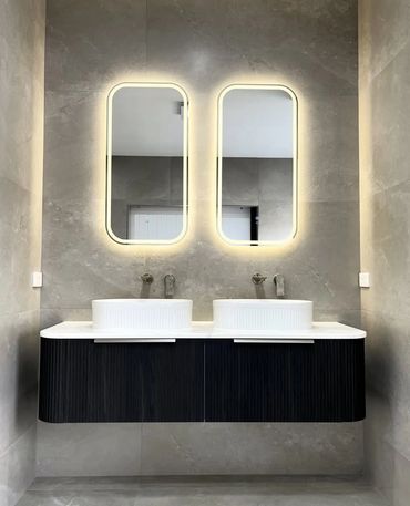 Bathroom with a floating double vanity, twin basins and illuminated mirrors.