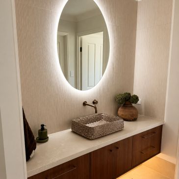Modern bathroom vanity with oval backlit mirror.