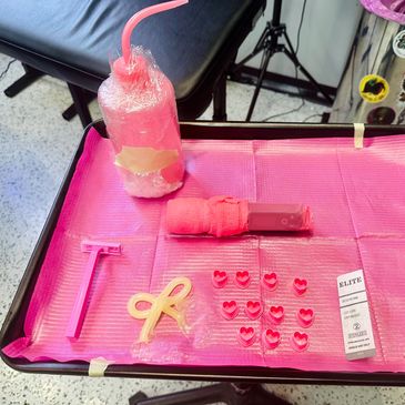 Pink tattoo tray setup with heart ink caps and a bow