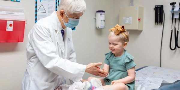 Doctor examining a toddler girl in a medical office.
