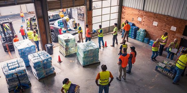 Volunteers organizing and distributing bottled water in a warehouse.