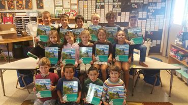 a group of childer holding aloha books