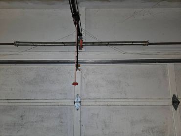 Close-up of a garage door spring and mechanism on a dirty garage door.