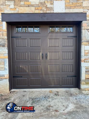 Brown garage door with stone wall and decorative handles.