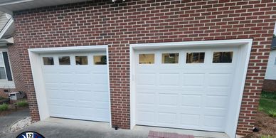 Two white garage doors on a red brick house exterior.